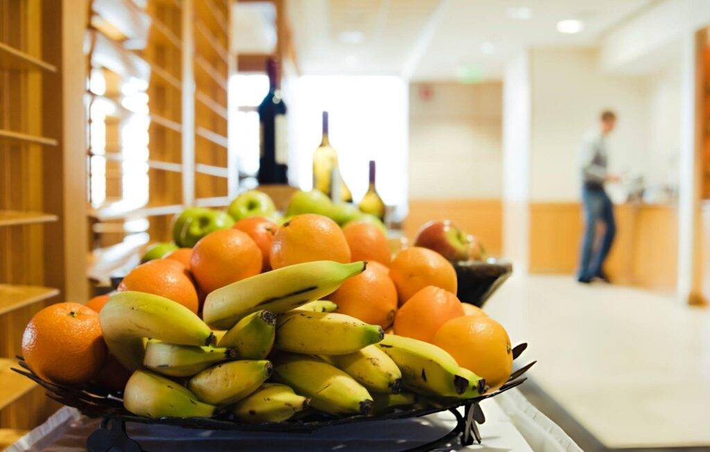 Un plateau de fruits colorés comprenant des bananes, oranges et pommes sur une table en bois.